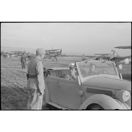 A bord d'un cabriolet Auto-Union, un capitaine (peut-être l'Hauptmann Joseph Karl) Gruppenkommandeure III./LLG.1 inspecte l'aérodrome de Valence-Chabeuil (Drôme) avant une mission.