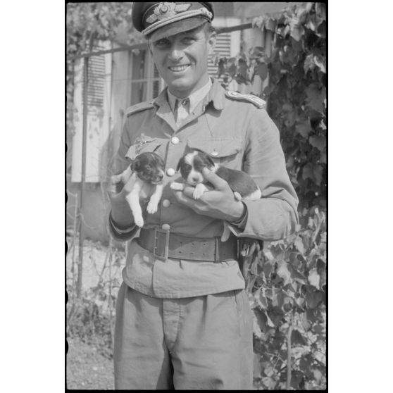 Sur l'aérodrome de Valence-Chabeuil (Drôme), un officier de la 1re escadre aéroportée (Luftlandegeschwader 1) en compagnie de deux chiots.