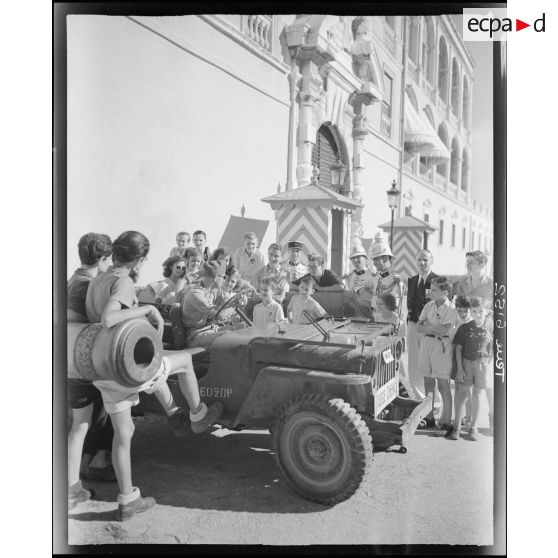 Une jeep Willys du service cinématographique de l'Armée (SCA) stationne devant le palais princier de Monaco.