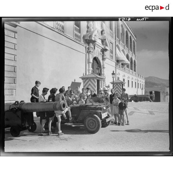 Une jeep Willys du service cinématographique de l'Armée (SCA) stationne devant le palais princier de Monaco.