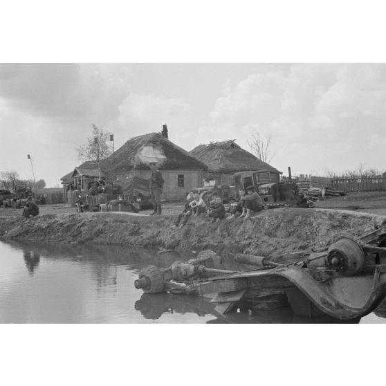 Une colonne de semi-chenillés Sd.kfz.10/5 FlaK 38 du Leichte Flak Abteilung 71 (11.Panzer-Division) marque un arrêt dans un village marqué par les combats.