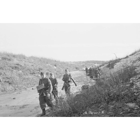 Une patrouille allemande progresse le long d'une rivière.