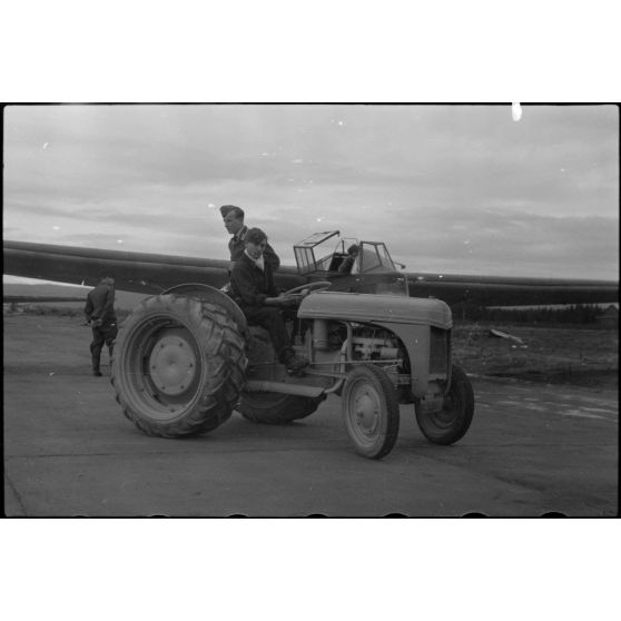 Sur la piste du terrain d'aviation, un tracteur agricole tracte le planeur DFS-230 du Luftlandegeschwader 1 (8./LLG 1) vers un nouvel emplacement.