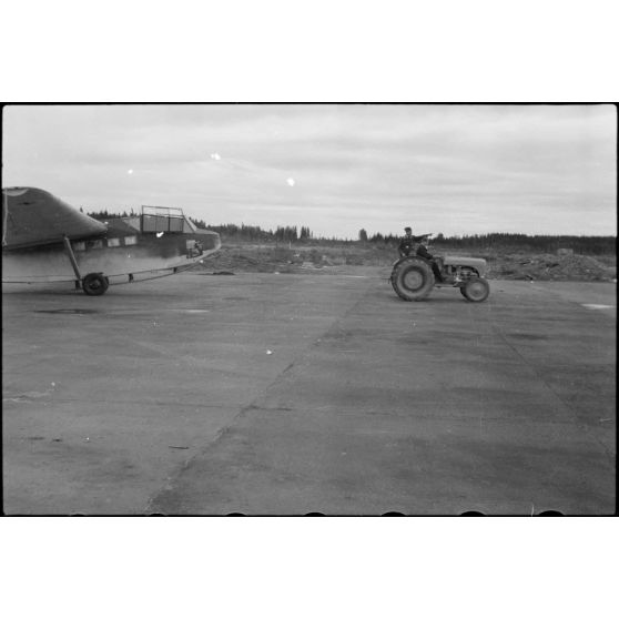 Sur la piste du terrain d'aviation, un tracteur agricole tracte le planeur DFS-230 du Luftlandegeschwader 1 (8./LLG 1) vers un nouvel emplacement.