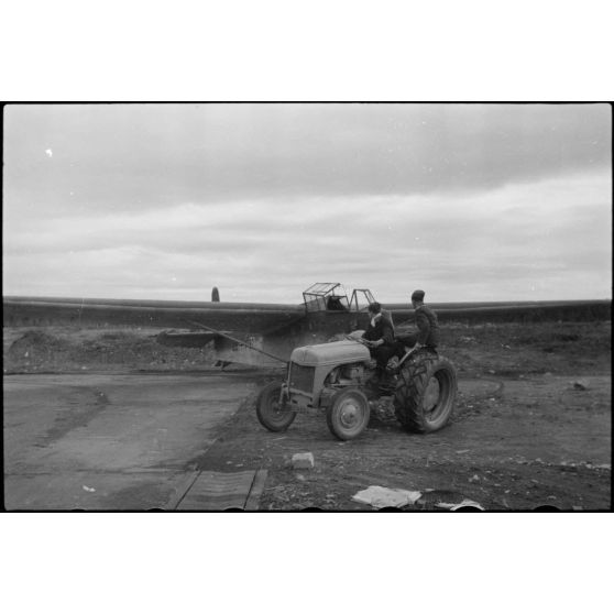 Sur la piste du terrain d'aviation, un tracteur agricole tracte le planeur DFS-230 du Luftlandegeschwader 1 (8./LLG 1) vers un nouvel emplacement.