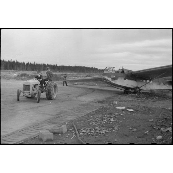 Sur la piste du terrain d'aviation, un tracteur agricole tracte le planeur DFS-230 du Luftlandegeschwader 1 (8./LLG 1) vers un nouvel emplacement.