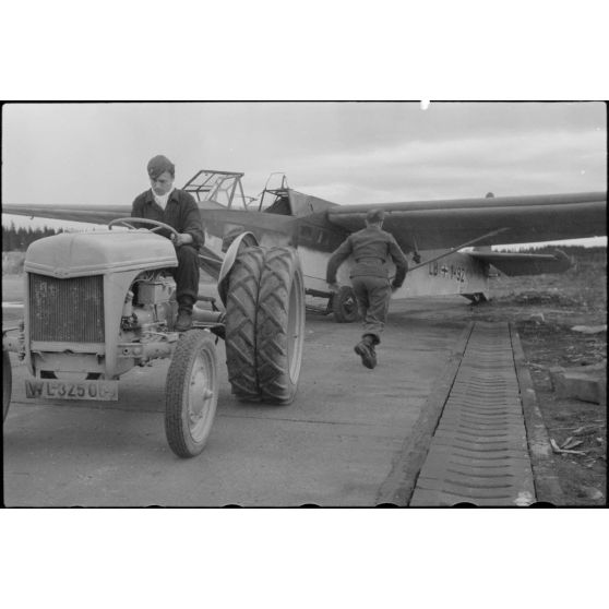 Sur la piste du terrain d'aviation, un tracteur agricole tracte le planeur DFS-230 du Luftlandegeschwader 1 (8./LLG 1) vers un nouvel emplacement.