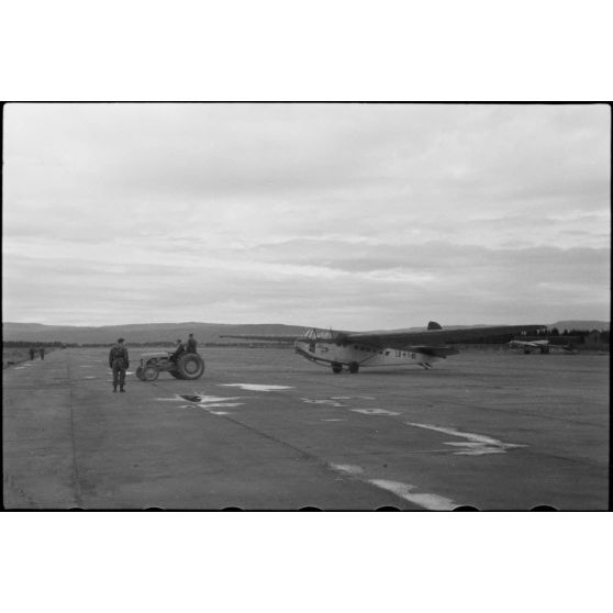 Sur la piste du terrain d'aviation, un tracteur agricole tracte le planeur DFS-230 du Luftlandegeschwader 1 (8./LLG 1) vers un nouvel emplacement.