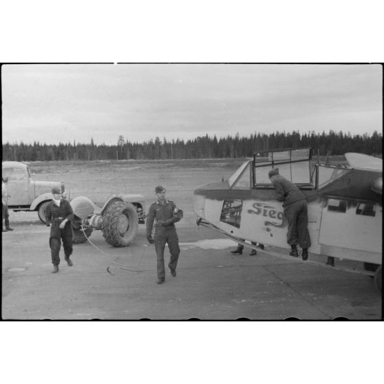 Sur la piste du terrain d'aviation, un tracteur agricole tracte le planeur DFS-230 du Luftlandegeschwader 1 (8./LLG 1) vers un nouvel emplacement. Le planeur est baptisé "Sieg" (immatriculation LB+1-92).