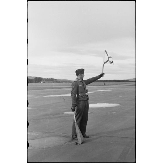 En Norvège, sur le terrain de Banak où stationne le 8./LLG 1 (Lulftlandegeschwader 1), un adjudant-chef (Oberfeldwebel) donne le signal du décollage des avions.