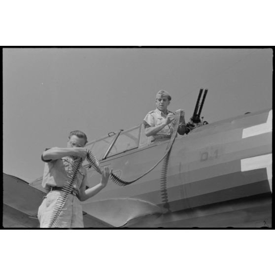 Sur la base de Skaramangas, deux mécaniciens de bord du Seeaufklärungsgruppe 126 approvisionnent les mitrailleuses MG-81 d'un hydravion Arado Ar-196 codé D1+BK.