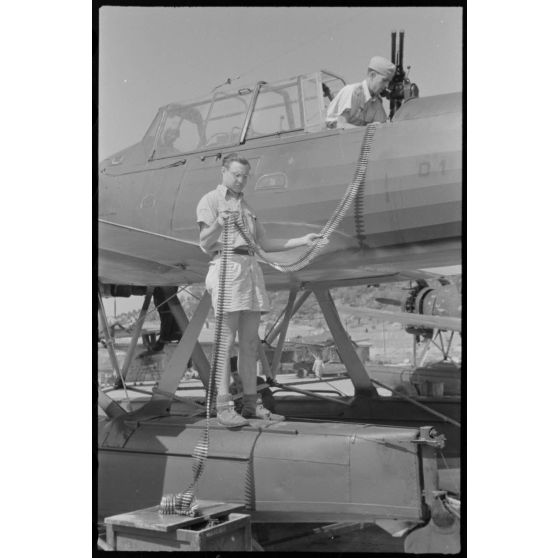 Sur la base de Skaramangas, deux mécaniciens de bord du Seeaufklärungsgruppe 126 approvisionnent les mitrailleuses MG-81 d'un hydravion Arado Ar-196 codé D1+BK.