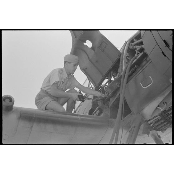 Sur la base de Skaramangas occupée par le 1er groupe du Seeaufklärungsgruppe 126, des mécaniciens approvisionnent la mitrailleuse MG-17 située sous le capot moteur de l'Arado Ar-196.