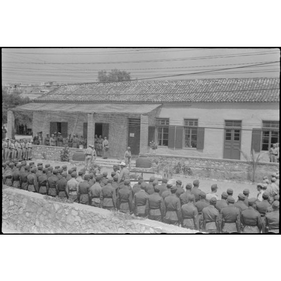 Devant le foyer du soldat (Soldatenheim) de Skaramangas, un général de l'armée de terre allemande commande une prise d'armes.