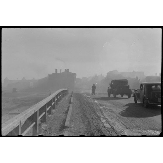 Des véhicules allemands patientent sur un pont avant de quitter Wjasma (Viazma), un insigne en forme d'écu pourrait correspondre au 9e corps d'armée (IX.Armeekorps).