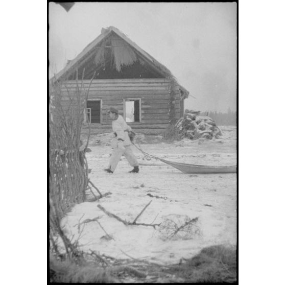 Lors de la bataille de Witebsk, un fantassin tire une luge dans les ruines d'un village.