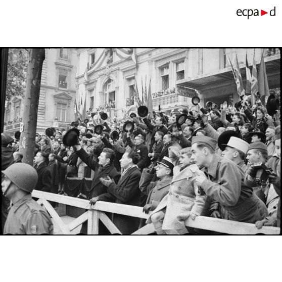 Foule immense acclamant le passage du général de Gaulle et de Winston Churchill, suivis du cortège des officiels, lors de leur descente des Champs-Elysées à l'occasion de la cérémonie du 11 Novembre 1944 à Paris.