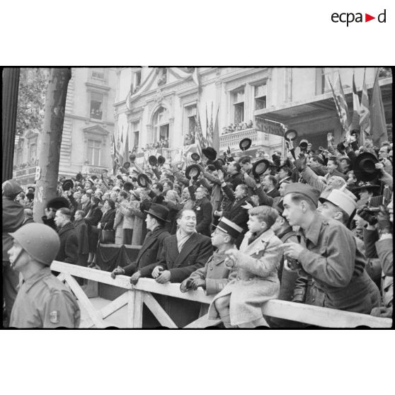 Foule immense acclamant le passage du général de Gaulle et de Winston Churchill, suivis du cortège des officiels, lors de leur descente des Champs-Elysées à l'occasion de la cérémonie du 11 Novembre 1944 à Paris.