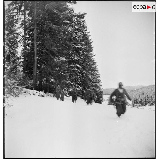 Tirailleurs sénégalais de la 9e DIC (division d'infanterie coloniale) progressant dans la forêt des Vosges enneigée, armés de pistolets-mitrailleurs Thompson M1A1.