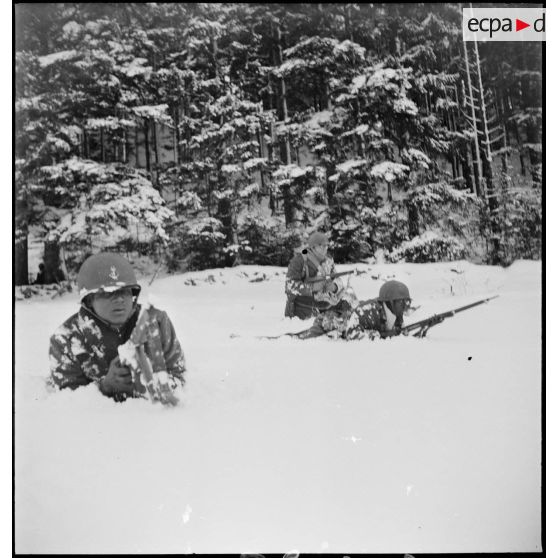 Tirailleurs sénégalais de la 9e DIC (division d'infanterie coloniale) progressant dans la forêt des Vosges enneigée, armés de pistolets-mitrailleurs Thompson M1A1 et de fusils Springfield M1903.