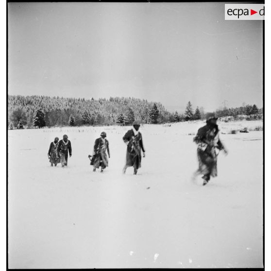 Tirailleurs sénégalais de la 9e DIC (division d'infanterie coloniale) progressant dans la forêt des Vosges enneigée, armés de pistolets-mitrailleurs Thompson M1A1.