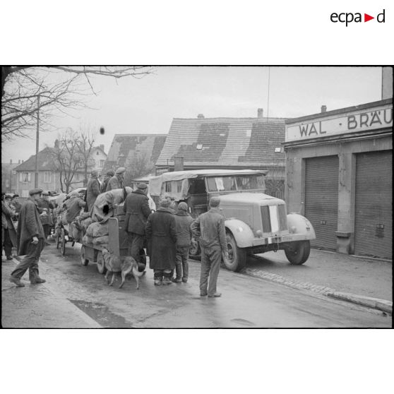 A Neudorf, avenue Jean Jaurès, les habitants du quartier du Port du Rhin (des ouvriers, polonais ou ukrainiens, requis par les autorités occupantes), se replient vers le centre de Strasbourg.<br>Semi-chenillé, tracteur d'artillerie ou de dépannage allemand, réquisitionné par la 2e DB.