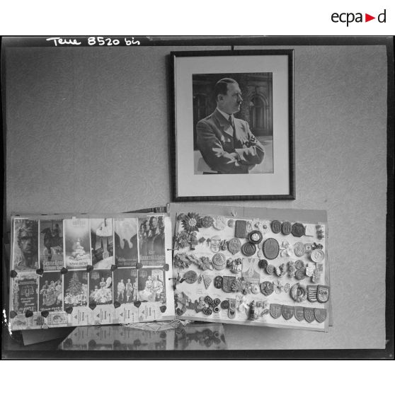 Album d'insignes nazis et portrait d'Adolf Hitler dans l'appartement d'un officier allemand investi par le 12e régiment de cuirassiers (12e cuirs) de la 2e division blindée (2e DB) près du pont de Kehl (Bas-Rhin).