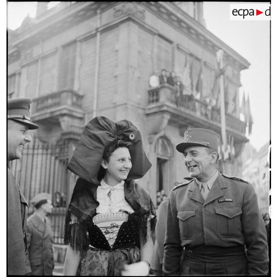 Le général de Lattre de Tassigny pose auprès d'une Alsacienne en costume traditionnel lors d'une cérémonie célébrant la libération de Belfort par les troupes de la 1re armée.