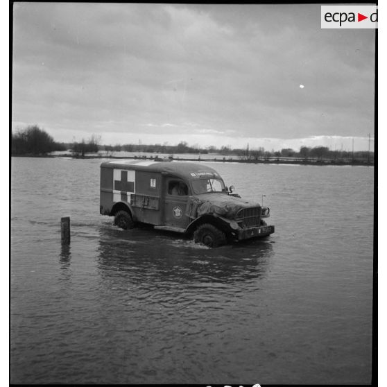 Le Dodge ambulance Cornebiche de la 2e DB traverse une zone inondée aux abords de l'Ill.