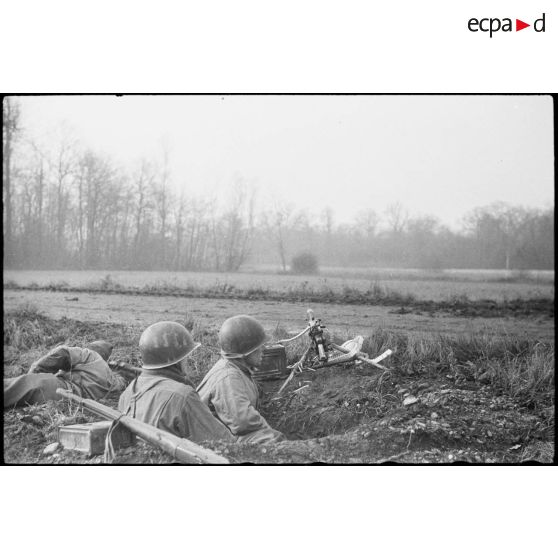 Dans le secteur de Benfeld et Wintternheim (Bas-Rhin), des fantassins, équipés d'une mitrailleuse de 30 mm, guettent à la lisière d'un bois, terrés dans un trou.