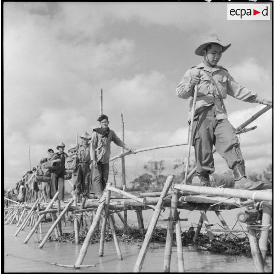 Des éléments du bataillon de marche indochinois (BMI) progressent sur un pont de bambous au cours de l'opération Marécages.