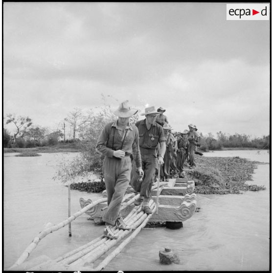 Passage d'éléments du bataillon de marche indochinois (BMI) sur un pont de bambous au cours de l'opération Marécages.