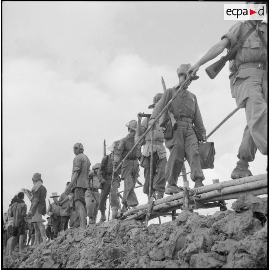 Passage d'un pont de bambous par des éléments du bataillon de marche indochinois (BMI) au cours de l'opération Marécages.