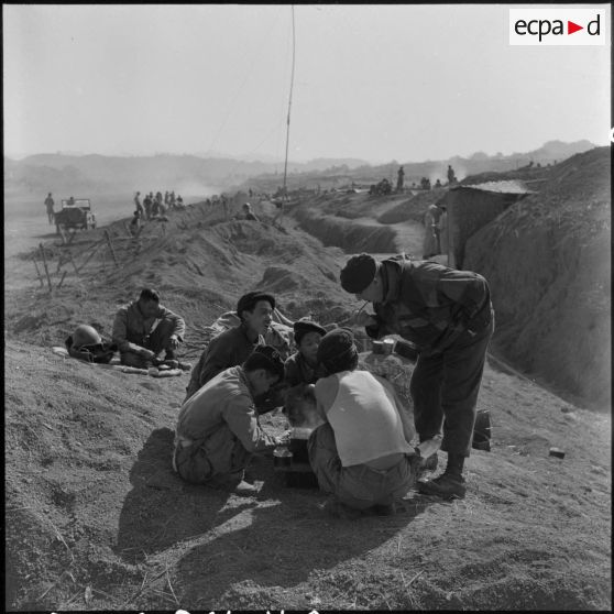 Le chef de bataillon Louis Fourcade, commandant le 1er BPC (bataillon de parachutistes coloniaux), goûte la cuisine de ses commandos vietnamiens, dans le camp retranché de Na San.