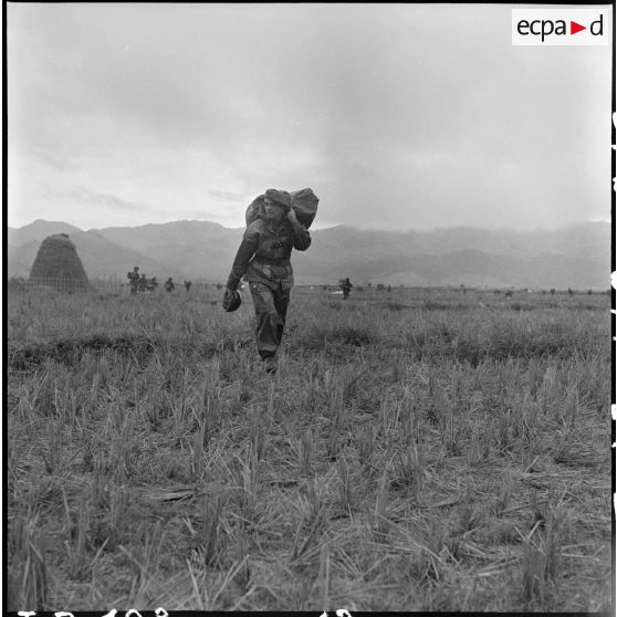 Portant son parachute replié, le général de brigade Gilles, commandant les troupes aéroportées en Indochine, s'avance vers le point de regroupement après son saut à Diên Bien Phu au cours de l'opération Castor.