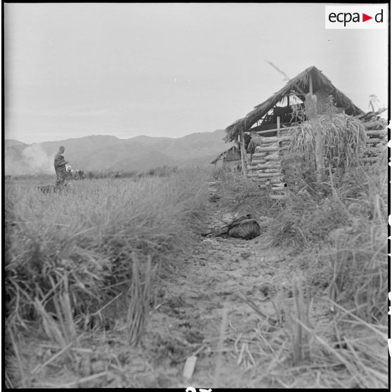 Les parachutistes prennent position dans la vallée au cours de l'opération Castor. Un soldat vietminh tué lors de l'opération gît au sol.