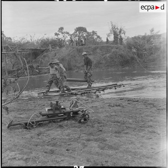 Des parachutistes transportent une pièce d'artillerie récemment parachutée en traversant la Nam Youm.