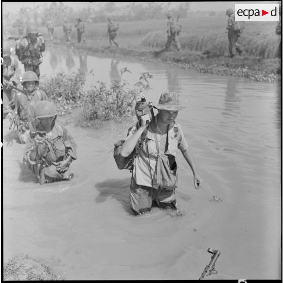 Traversée d'un arroyo par des éléments du 2e BEP avec le caméraman du SCA  André Lebon, lors de l'opération Brochet.