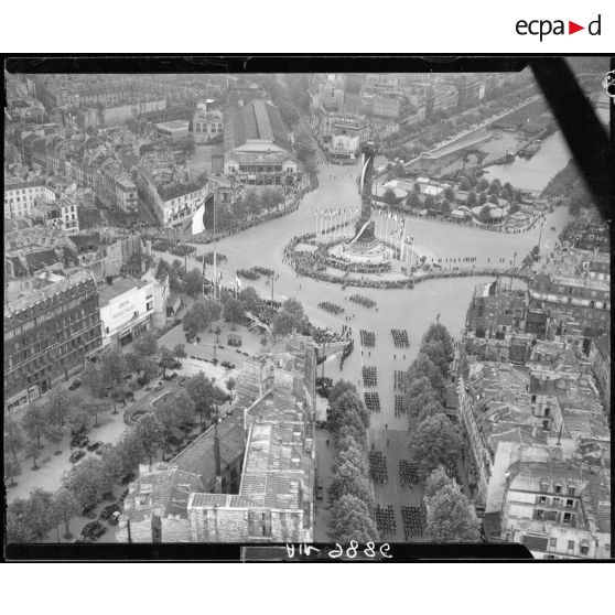 Vue aérienne des cérémonies du 14 juillet 1946 à Paris. Les ouvriers d’armement défilent place de la Bastille. En arrière-plan, le bassin de l'Arsenal, le cinéma Bastille Palace et le cinéma Lux.