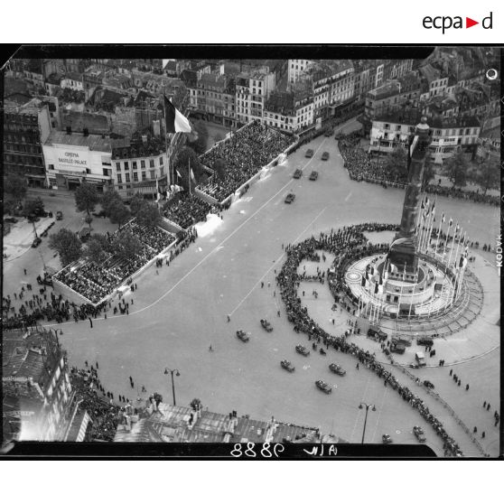 Vue aérienne des cérémonies du 14 juillet 1946 à Paris. Clôturant le défilé, les unités motorisées passent devant les tribunes sur la place de la Bastille. En arrière-plan, le cinéma Bastille Palace.