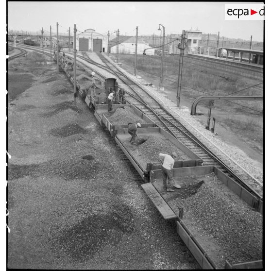 Des cheminots vident des wagons de ballast près de la gare ferroviaire de Massy.