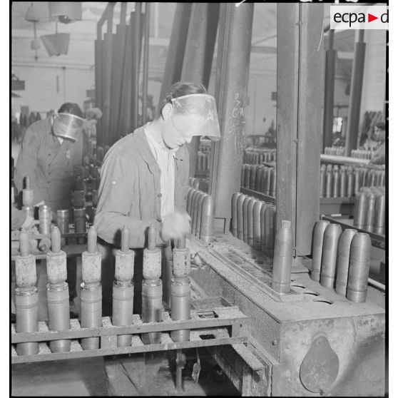 Plan général d'un atelier de l'usine de munitions où des ouvriers travaillent à la confection d'obus.