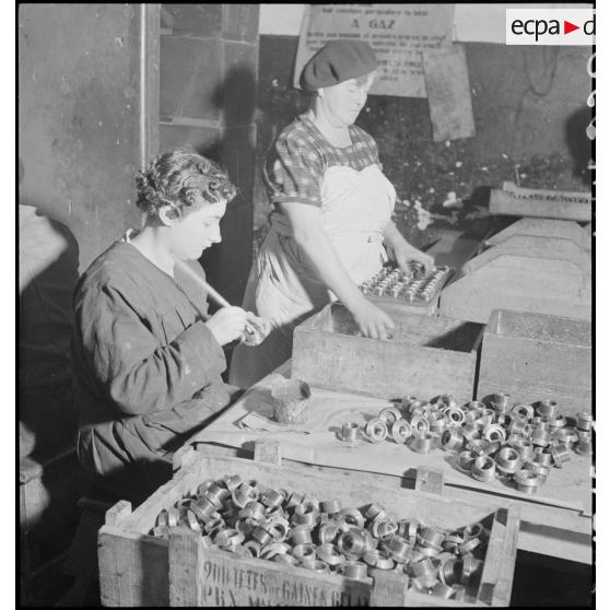 Plan général d'un atelier de l'usine de munitions où des ouvrières travaillent sur des corps de fusée d'obus de 75 mm.