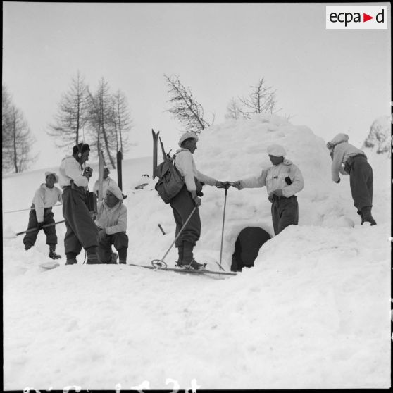 Des éclaireurs-skieurs s'affairent autour d'un igloo.