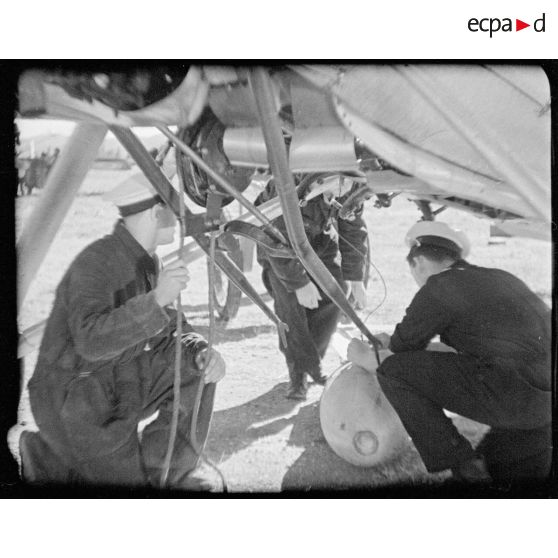 Mise en place d'une bombe ou d'une torpille sous un appareil de l'aéronautique navale.