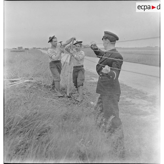 Officier marinier et marins posant du barbelé.