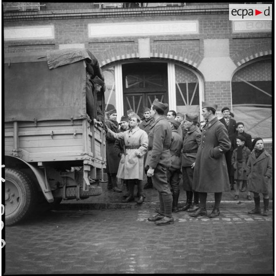 Photographie de groupe de soldats de la 1re armée regroupés près de l'arrière d'un camion.