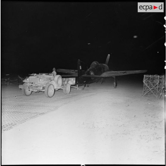 Remorquage de nuit d'un avion de chasse Beacat F8F par un véhicule Dodge sur le terrain d'aviation de Diên Biên Phu.