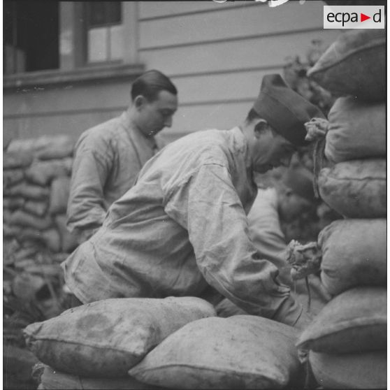 [Les soldats Victor Petit et Henri Goupy du SCA (service cinématographique de l'armée) préparant des sacs de sable.]