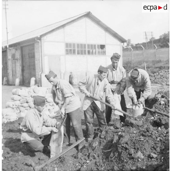 [Photographie de groupe d'une équipe du SCA (service cinématographique de l'armée) confectionnant des sacs de sable, Moulins-lès-Metz (Moselle), Septembre 1939.]